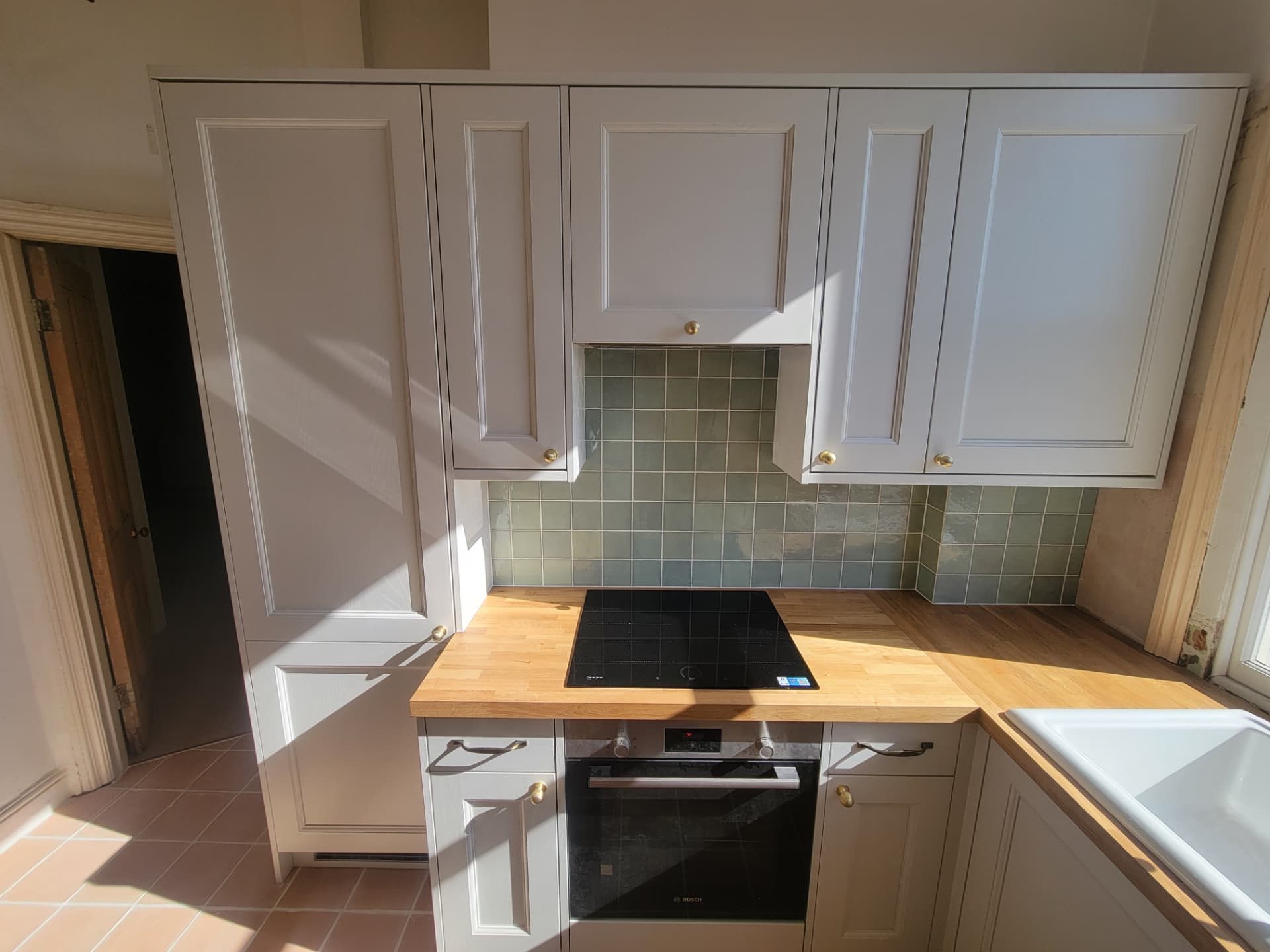 Shaker-style cabinetry, timber worktops and tiled splashback around the cooking area