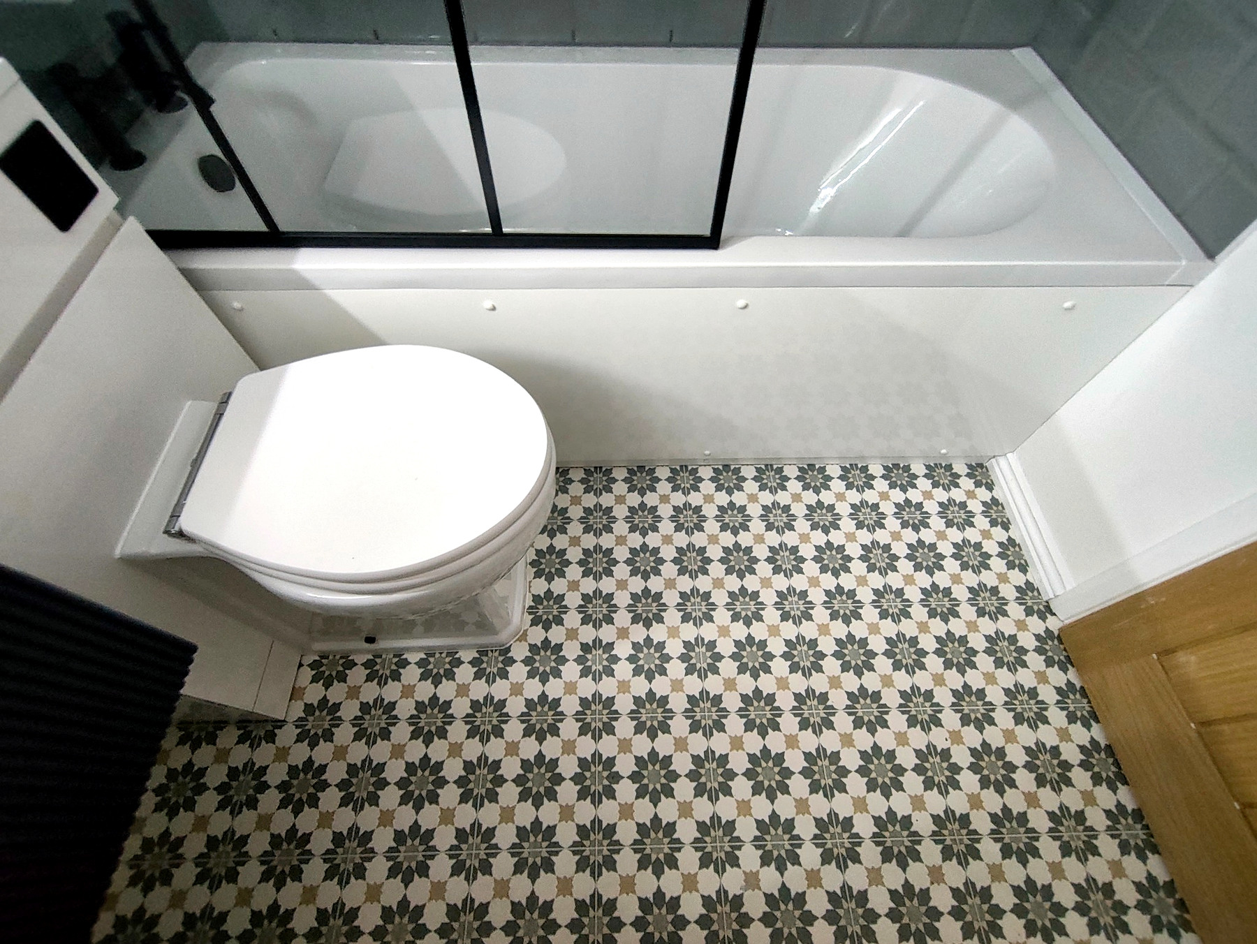 Patterned bathroom floor finish beside the bath