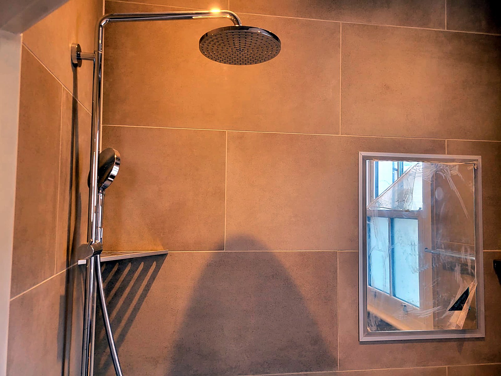 Wet room shower area with mirror and two-tone porcelain tiling