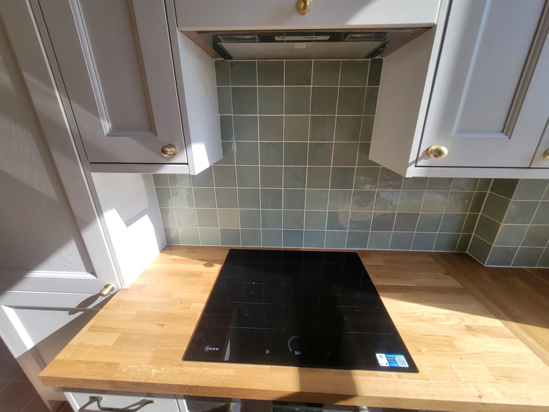 A closer view of the hob, timber worktop and tiled splashback