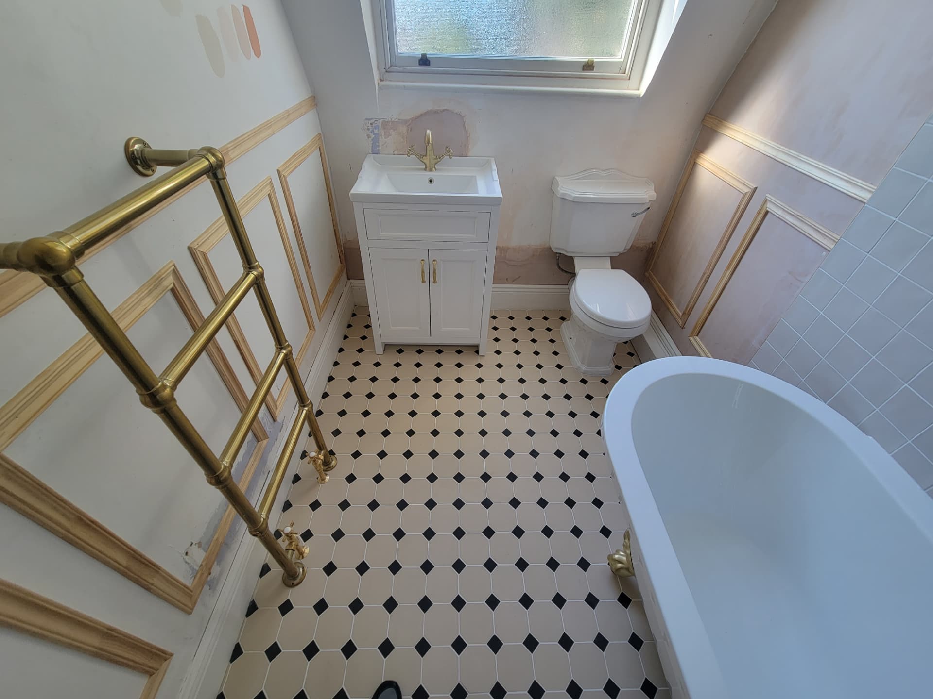 Vanity, WC, bath and brass towel rail above the patterned floor