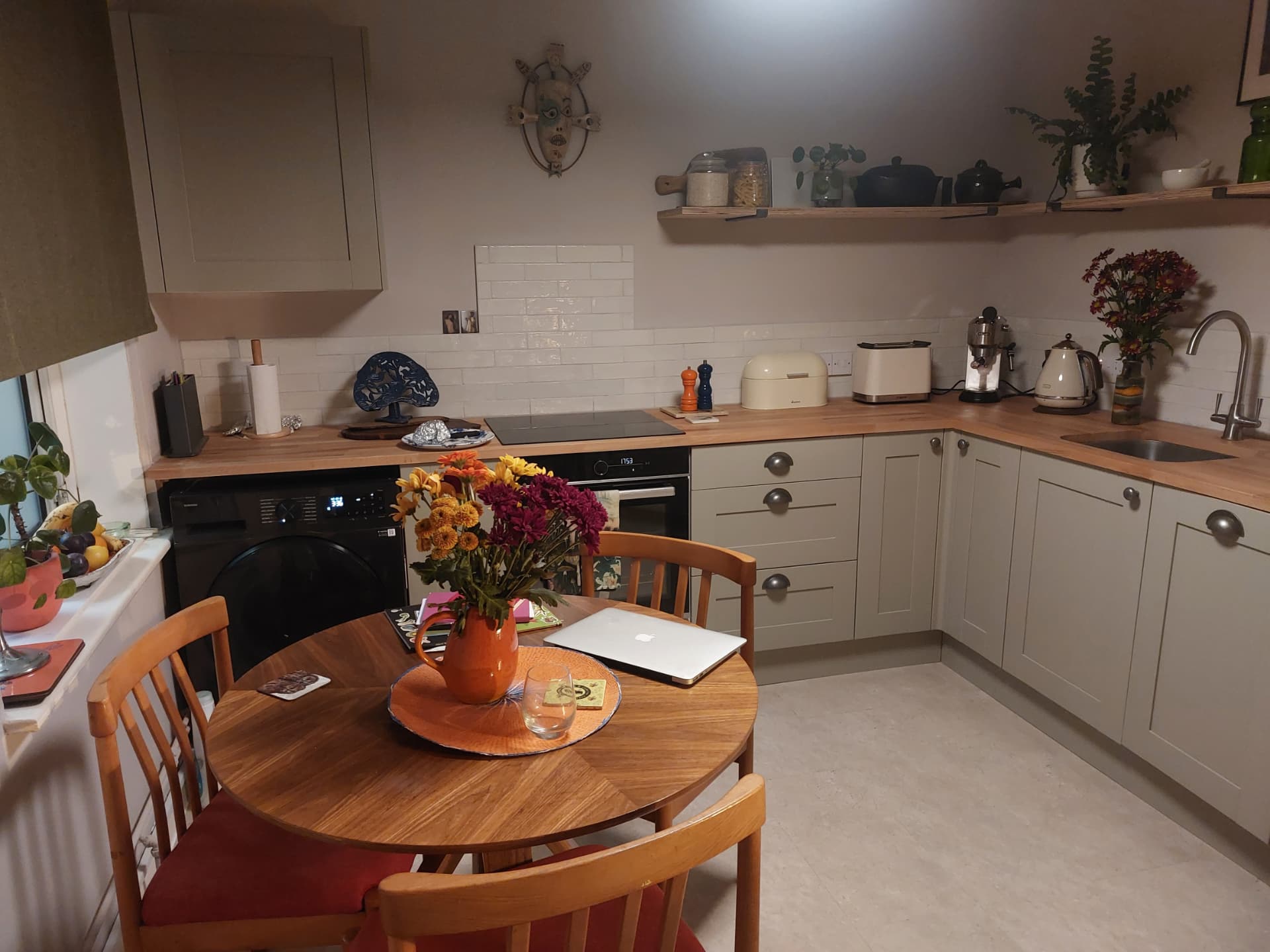 Finished kitchen with sage painted cabinets, solid timber worktops, white brick-effect tiles and open shelving