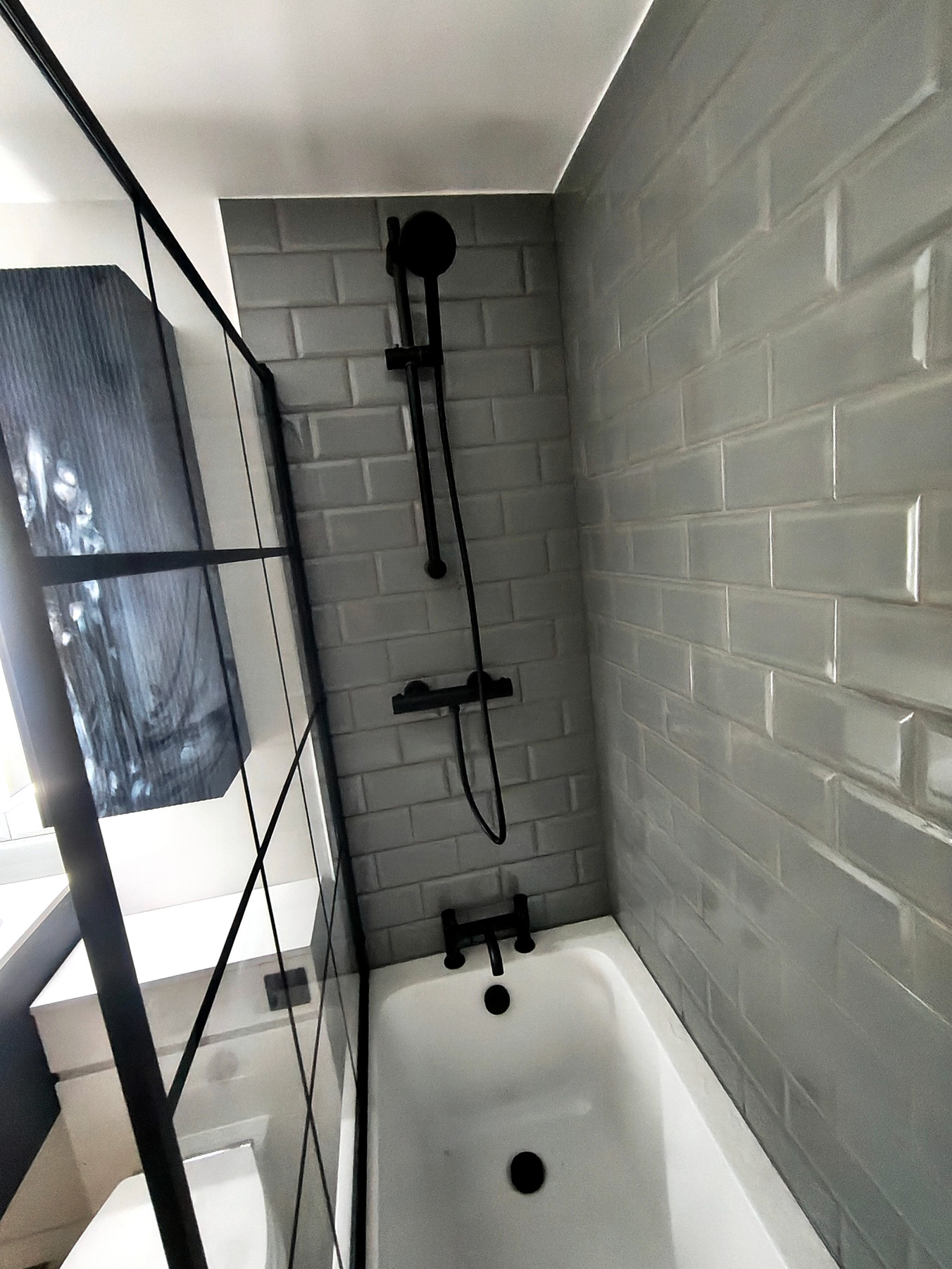 Black framed shower screen and tiled bath area
