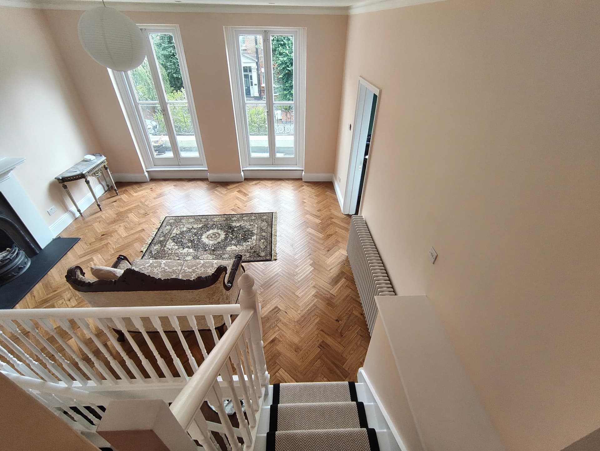 Landing looking down the stair runner into the drawing room with parquet flooring