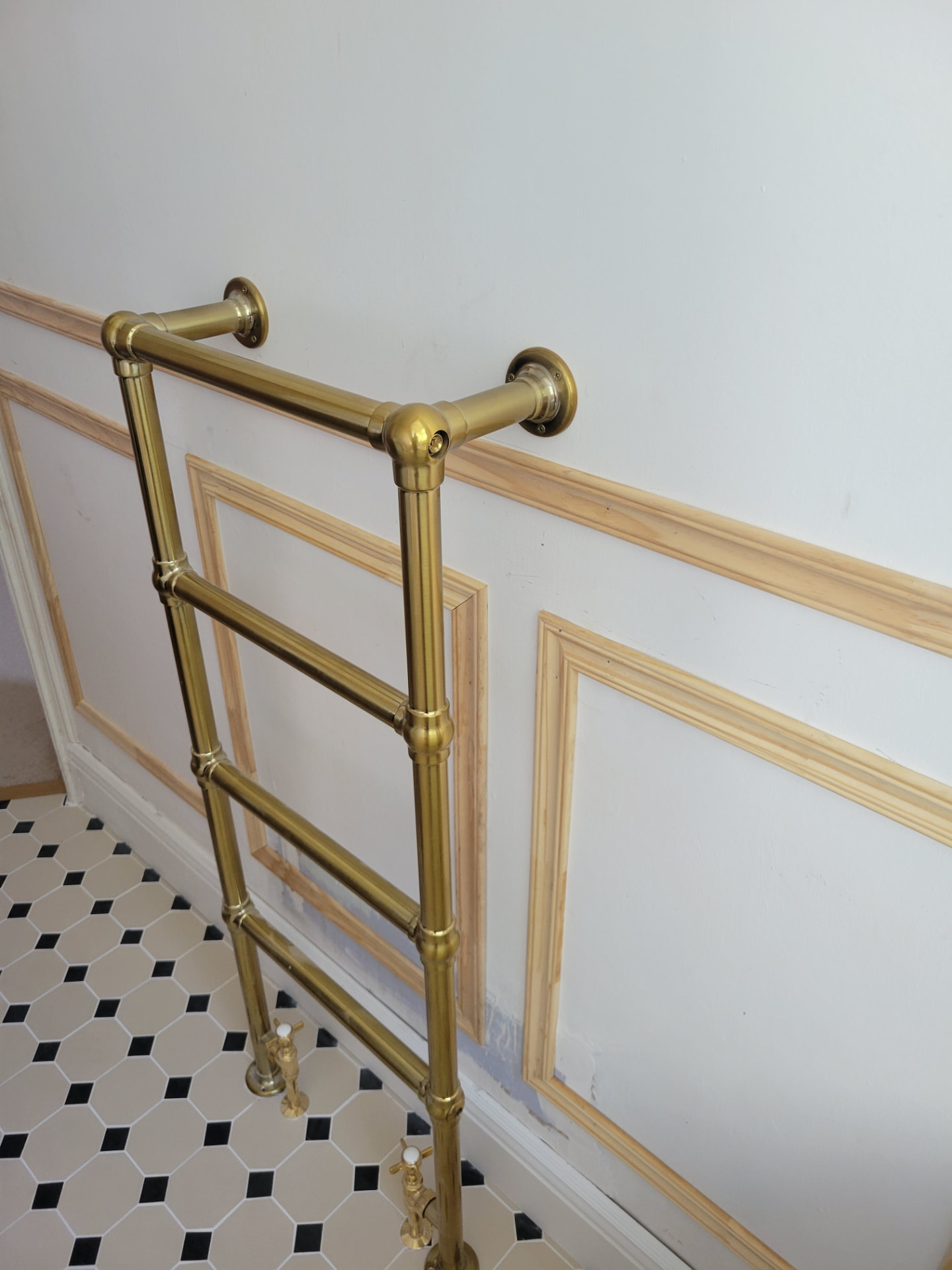 Brass towel rail beside the panelled wall and patterned floor
