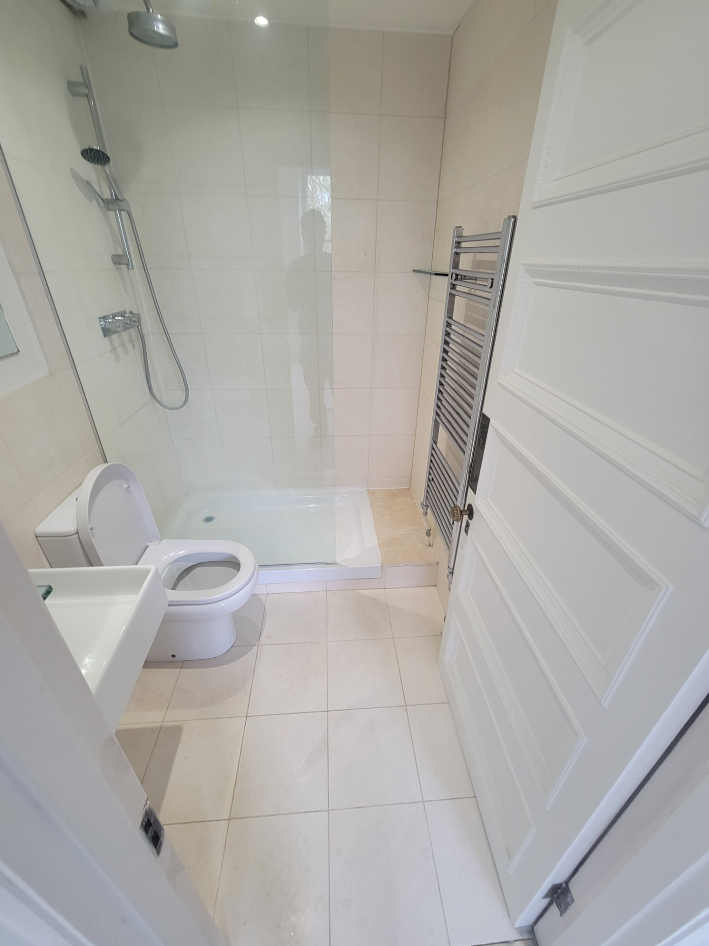 Original separate shower room before works with a corner shower tray, chrome towel rail and beige tiling