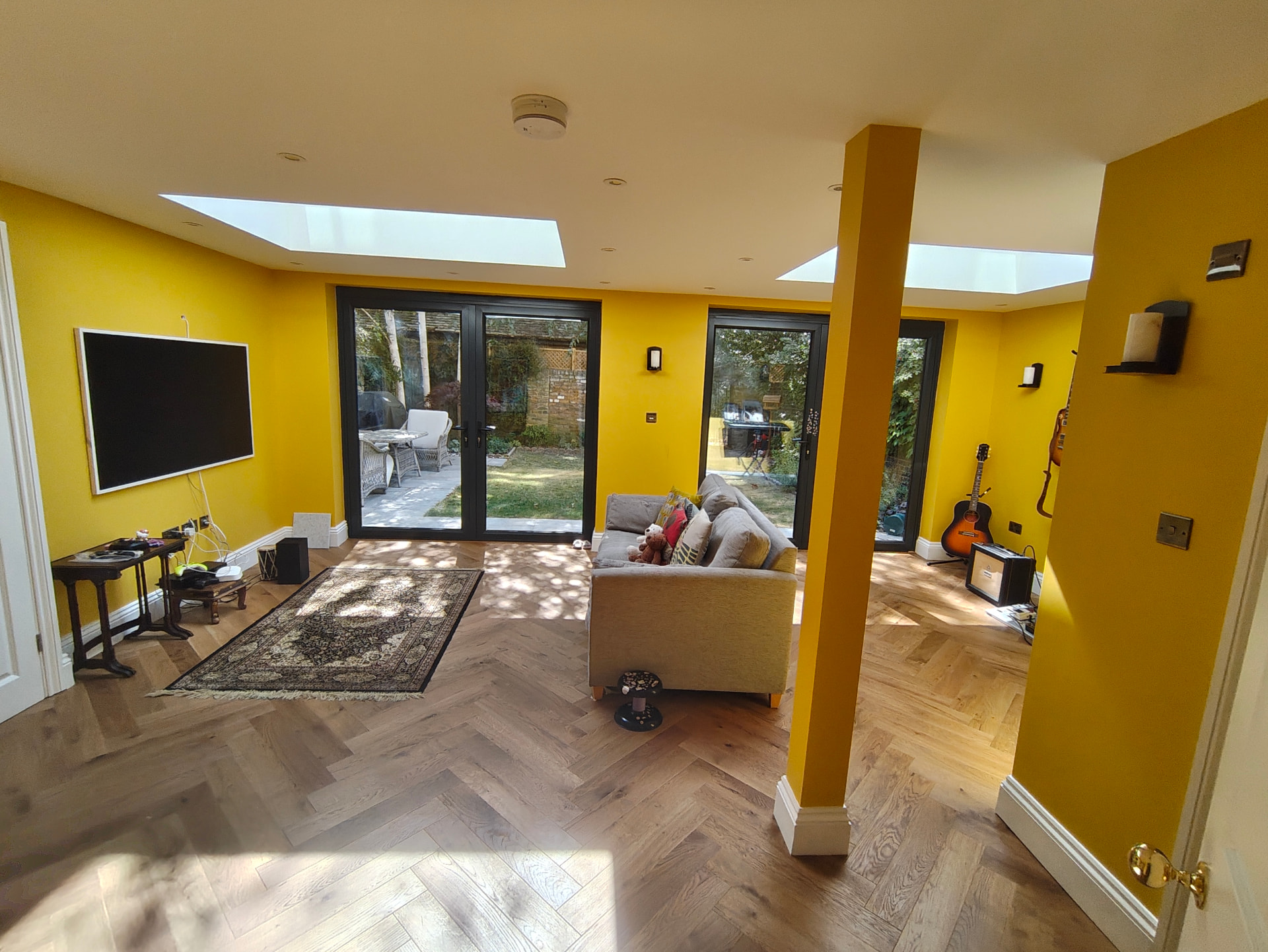 Music room formed by knocking two rear rooms together, with ochre yellow walls and oak herringbone flooring