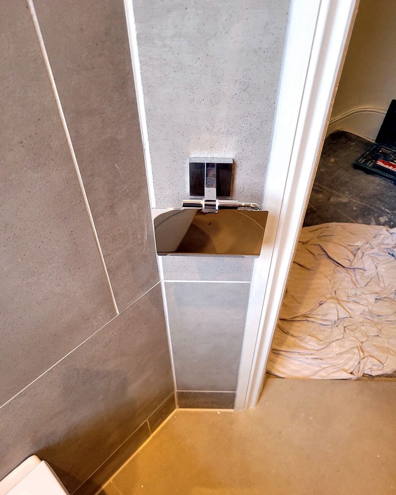 Concealed cistern flush plate set into the tiled wall above the WC