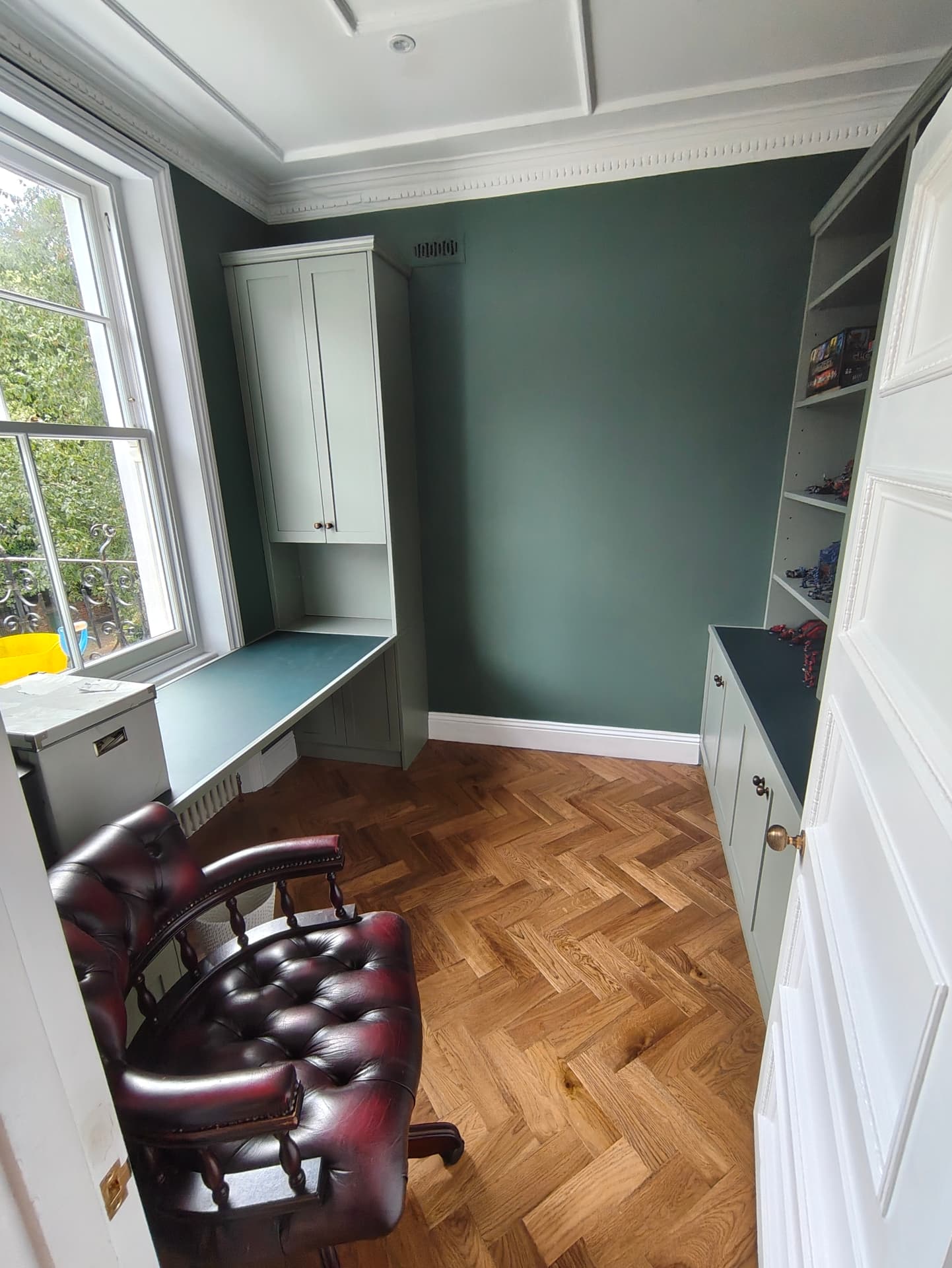 Fitted home study in deep green with bespoke desk, cupboards and shelving on herringbone parquet